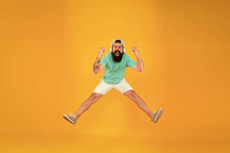 Like a rock star. happy guy wear headphones. summer vacation party. brutal hipster jump high. his favorite song. mature dj full of energy. feel freedom. celebrating success. bearded man listen musicの写真素材