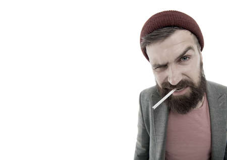 Brutal unshaven guy smoking isolated white background. Brutal habits and lifestyle of tramp. Hipster brutal bearded tobacco smoker. Man brutal bearded hipster dressed as vagabond smoking cigaretteの写真素材