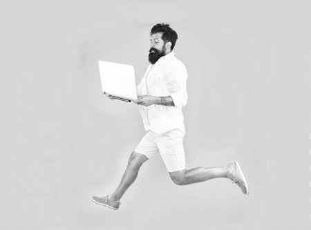 Portability concept. Remote job. Man inspired hold laptop jump. Run with laptop. Hipster bearded manager with laptop. Online shopping. Must have gadgets that we never leave home without. Keep movingの写真素材