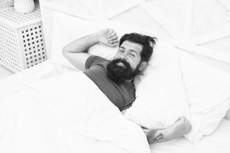 Great time at home. getting the rest your body needs. bed is so comfortable in morning. peaceful mature male relaxing on pillow. bearded man smiling in bed. sleepy guy relax in bedroom. early morningの写真素材