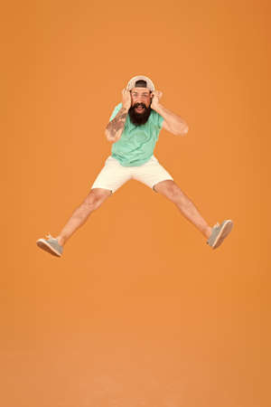 Dj cheerful guy. Amazing stereo sound. Summer party. Man listen music wireless headphones. Bearded guy enjoy music. Hipster jumping with earphones. Inspiring song. Music library. Invigorating musicの写真素材
