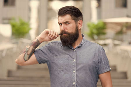 Obsessed about his mustache. Bearded man twirl mustache urban outdoor. Hipster wear long beard and mustache. Beard and mustache care. Barbershop. Barber shop. Products for growing and groomingの写真素材
