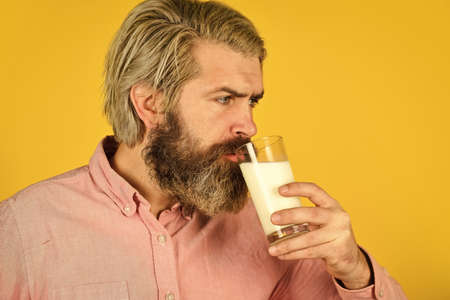 Pasteurized milk. Emotional bearded man hold glass of milk. Vegan milk concept. Vegan milks made from wide variety of beans nut, seeds and grains. Healthy food. Drink protein cocktail. Lactose freeの写真素材
