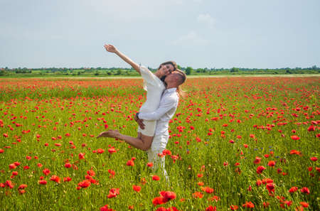 romantic relationship. beautiful couple in love. man and woman in poppy flower field. summer vacation. happy family among red flowers. spring nature beauty. love and romance. We are strongの写真素材