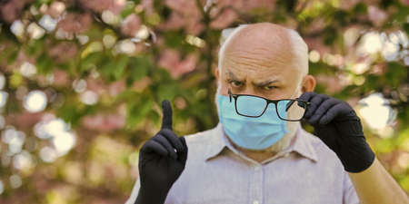 man in mask and gloves hold glasses, selective focus. sakura blossom tree in park. coronavirus covid19. spring enjoyment. restricted sakura park. park is closed for quarantine due to coronavirusの写真素材