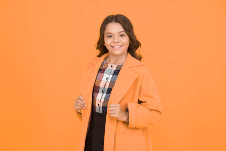 Yellow mood. Girl fashionable cute model wear yellow wool coat. Personal styling and bespoke tailoring. Feeling cozy and comfortable. Fancy child smiling face on yellow background. Yellow colorの写真素材