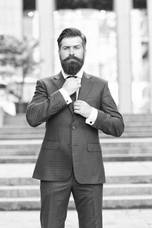 Boutique to you. Confident and handsome. serious bride groom fixing tie outdoor. brutal male beauty. formal and office fashion. man in suit that fixed tie. leadership concept. Businessman wear jacketの写真素材