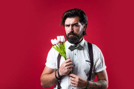 brutal bearded man holding beautiful blossoming bouquet of fresh tulips flowers, fathers dayの写真素材