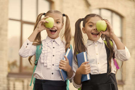 lunch time at school break. happy kids in uniform. learning subject together. modern education for girls. book reading. concept of friendship. little pupil with notebook and appleの写真素材