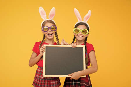 happy childhood concept. small girls bunny ears yellow background. funny little sister kids celebrate easter. egg hunt begin. traditional spring holiday. copy space. happy easter. spring is comingの写真素材