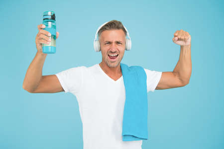 Staying hydrated staying healthy. Healthy and strong man on blue background. Happy athlete celebrate...