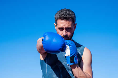 man boxer punching. fitness gym outdoor. muscular athletic guy training in boxing gloves