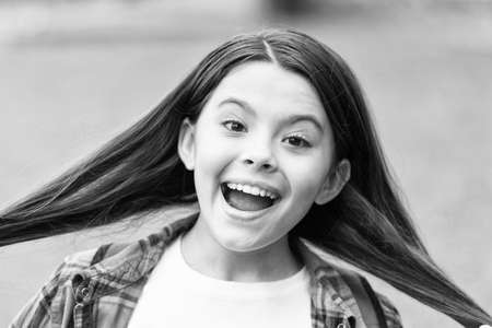 Because we obsess about your hair. Happy girl hold silky long hair outdoors. Beauty look of little child. Hair salon. Shampoo and conditioner. Expert care for every haircare needの写真素材