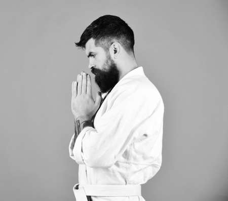 Judo master holds hands together in traditional greeting or prayer. Karate man with concentrated face in uniform.の写真素材