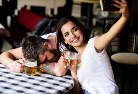 Girl taking selfie photo drunk boyfriend. Take selfie to remember great event. Man drunk fall asleep...