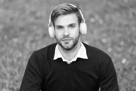 education with ebook. man with bristle in headset listening music while relax in park. guy learning with audio book. get useful information. man enjoy song. students lifeの写真素材