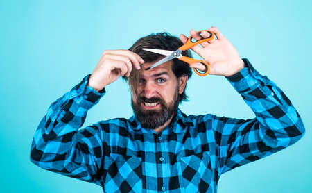 brutal man in checkered shirt has long beard cut hair with scissors, hairdresser