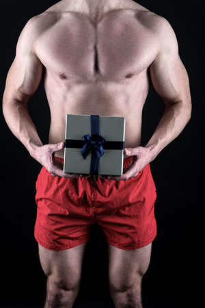 Sexy surprise concept. Macho muscular torso posing with gift box. Santa claus for adult girls. Sexy athletic macho muscular chest. Athlete man has gift for you. I have gift for you. Valentines dayの写真素材