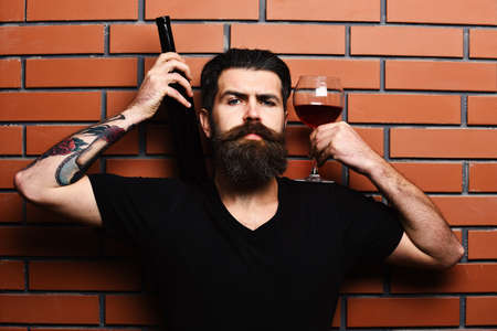 Macho with confident face presents red cabernet or merlot.の写真素材