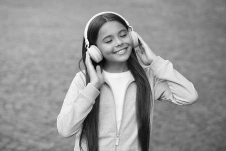 cheerful girl wear earphones with music song outdoor enjoying melody, school online educationの写真素材