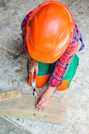 teen girl builder in protective helmet use hammer, constructionの写真素材