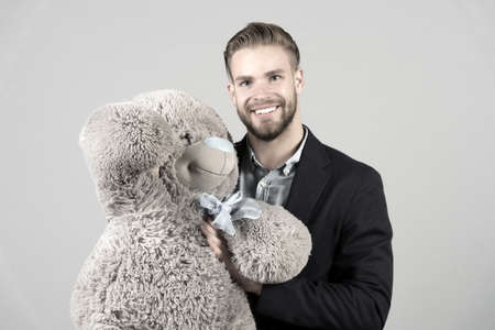 It is never too late to have happy adulthood. Man hols big teddy bear, grey background. Birthday gift concept. Teddy bear pleasant surprise. Guy happy hold bear. Man cute gift surprise. Grown kidの写真素材