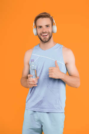 Drinking water. Cheerful athletic guy listening music. Keep body and mind in good shape. Happy...