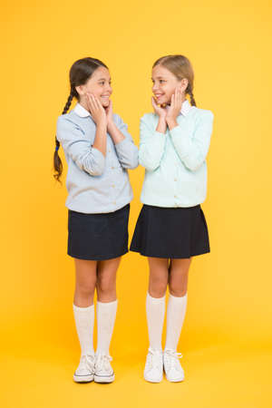 Look at this. kid fashion. Friendship and sisterhood. education concept. back to school. happy girls in school uniform. smart little girls on yellow background. knowledge day. childhood happinessの写真素材