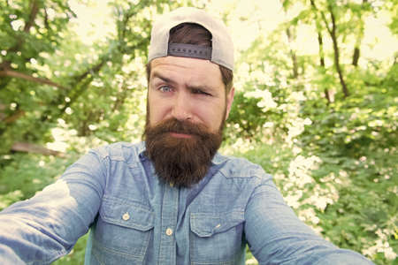 Watch nature closely. ready for camping. male amazed tourist wear cap. sport and fitness clothes. Confident and handsome brutal man. brutal caucasian hipster with moustache. Bearded man make selfieの写真素材