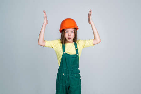 girl child wearing uniform and helmet while working in workshop, overworkedの写真素材