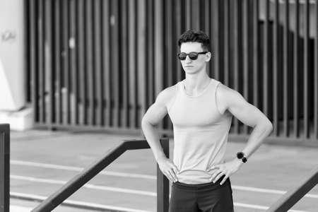 Handsome sportsman in sunglasses ready for morning jog at stadium