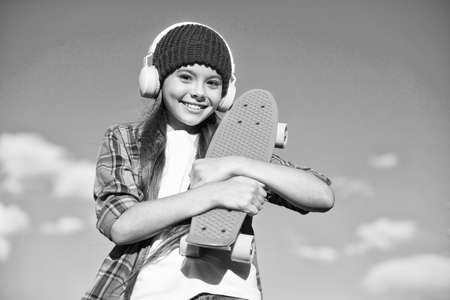 Just a little more plastic underfoot. Happy skater on blue sky. Small kid hold penny board. Riding penny skateboard. Speed and balance. Summer vacation and holidays. Penny board for beginnerの写真素材