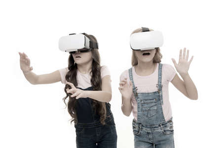 Virtual reality is exciting. Girls little kids wear vr glasses white background. Virtual education concept. Modern life. Interaction in virtual space. Cyber gaming. Augmented reality technologyの写真素材