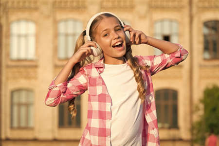 Learning concept. Home schooling online education. Smiling schoolgirl. Wherever i go. Back to school. Small girl in headphones. Listening audio book. Free ebook. Girl in headphones listening musicの写真素材