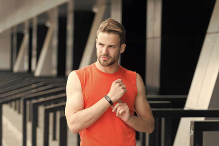 Just keep moving. Sportsman training with pedometer gadget at stadium. Sport gadget concept. Man athlete strict face with sport equipment, urban background. Athlete fitness tracker or pedometerの写真素材