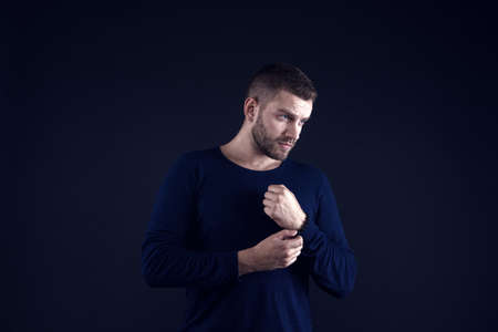 Man touch bead bracelet on hand on dark background