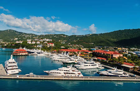 yachts moored at sea pier on mountain landscape. Sea port and town on sunny blue sky. Luxury travel on boat, water transport. Vacation on island.のeditorial素材