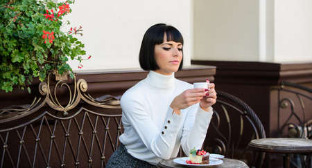 Dessert concept. Pleasant time and relaxation. Delicious and gourmet snack. Girl relax cafe with coffee and dessert. Woman attractive elegant brunette enjoy dessert and coffee cafe terrace backgroundの写真素材