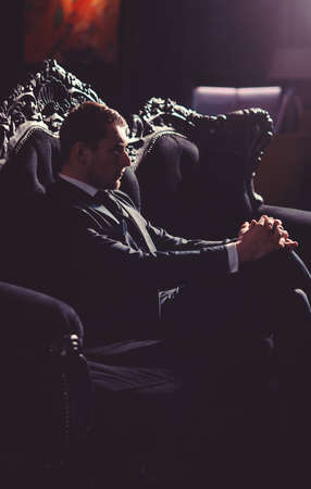 Lawyer with serious unshaven face. Businessman sits on elegant vintage sofa and thinks. Professional success, business, fashion, wealth concept. Director in fashionable suit looks respectableの写真素材