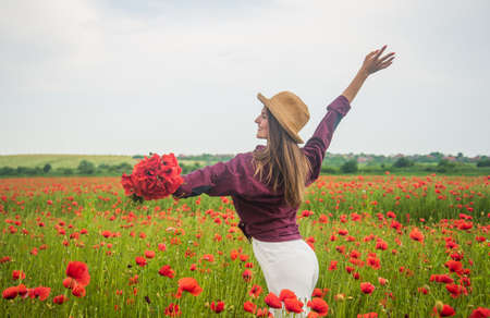 Young beautiful girl in spring walking in amazing poppy field, happinessの写真素材