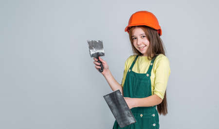girl kid in hard hat on construction site use spatula, helpの写真素材