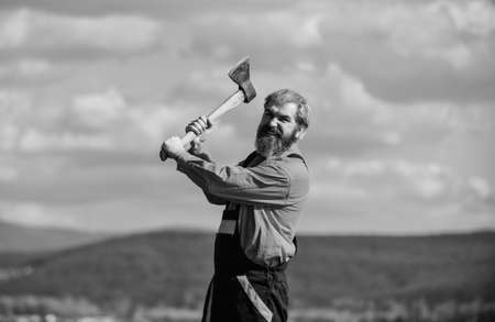 Use axe construction. Hard labour. Renovation tools. Handsome guy brutal temper. Professional occupation. Man in uniform hold ax. Brutal bearded man axe in hands. Brutal and bearded. Builder with axeの写真素材