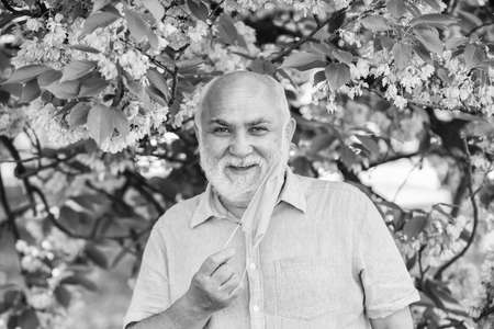 Respiratory condition. Difficulty in breathing. Allergic reaction. Limit risk infection spreading. Senior man face mask. Respiratory mask. Asthma treatment concept. Pollen allergen. Man and flowersの写真素材