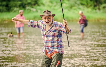 Moments of buying best. summer weekend. fisherman with fishing rod. mature man fishing. sport activity and hobby. Trout bait. pothunter. man catching fish. retired bearded fisher. big game fishingの写真素材