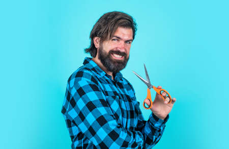 barbershop. smiling barber use scissors. trendy man using scissors for cutting hair. confident man at hairdresser salon. masculinity and charisma. bearded hipster cut his beard and moustacheの写真素材