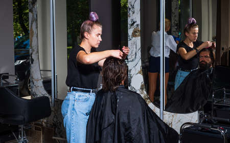 the guy is a dark-haired caucasian appearance on a haircut in a barbershop, hairdressing