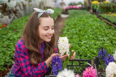 happy teen girl florist care pot plants in greenhouse, horticulture