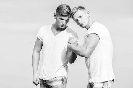 Men twins brothers muscular guys in white shirts sky background. Brotherhood concept. Benefits of...