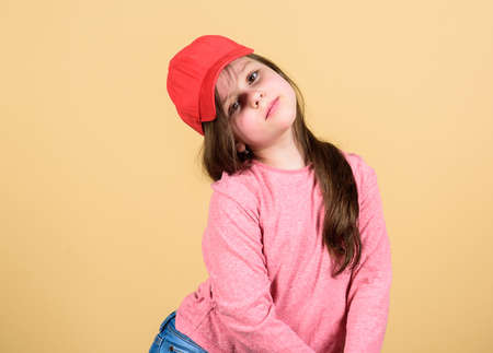 Little girl wearing bright baseball cap. Modern fashion. Kids fashion. Stylish accessory. Feeling confident with this cap. Cutie in cap. Girl cute child wear cap or snapback hat beige backgroundの写真素材
