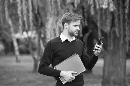 business communication. get useful information from smartphone. man read message. students life. education with modern technology. smart man using mobile phone. guy holding notebook for making notesの写真素材